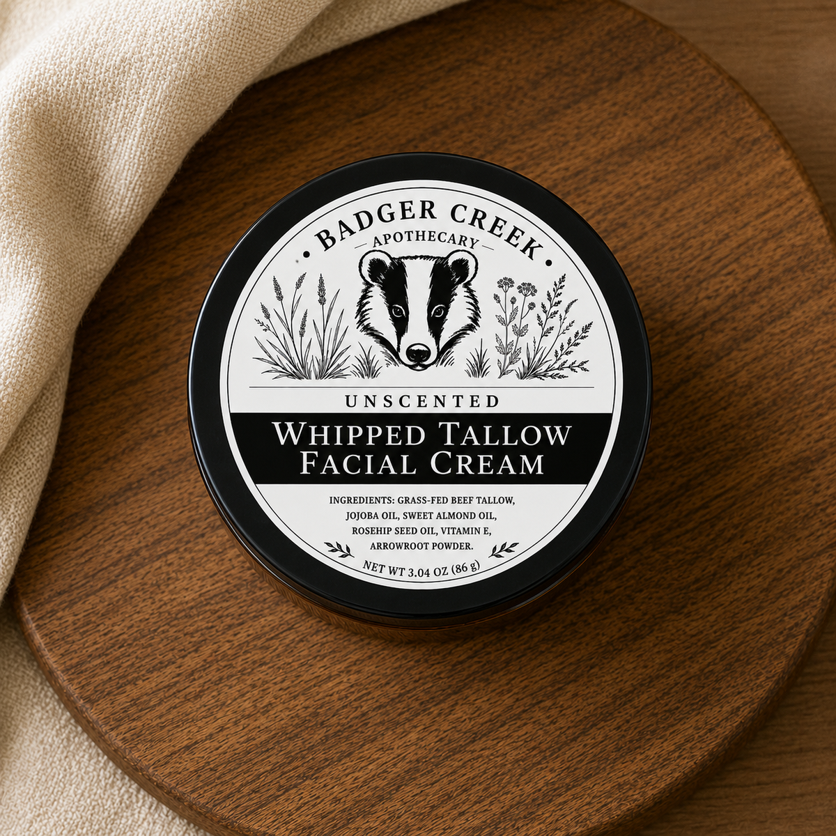 A round bcontainer of Badger Creek Apothecary Unscented Whipped Tallow Facial Cream sits on a round wooden board with a beige cloth beside it. The front label shows a black-and-white badger illustration and product text.